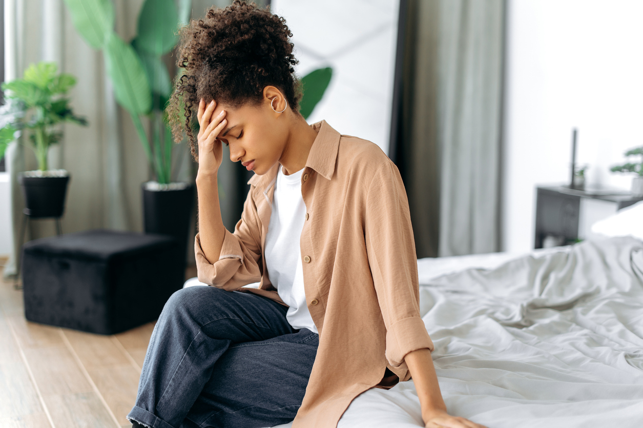Woman with a concussion sitting on a bed feeling uncomfortable.